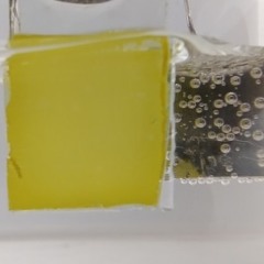A oxidação da glicerina acontece no fotoanodo de vanadato de bismuto (amarelo) enquanto o hidrogênio (bolhas) é gerado no outro eletrodo (imagem: divulgação/CINE)
